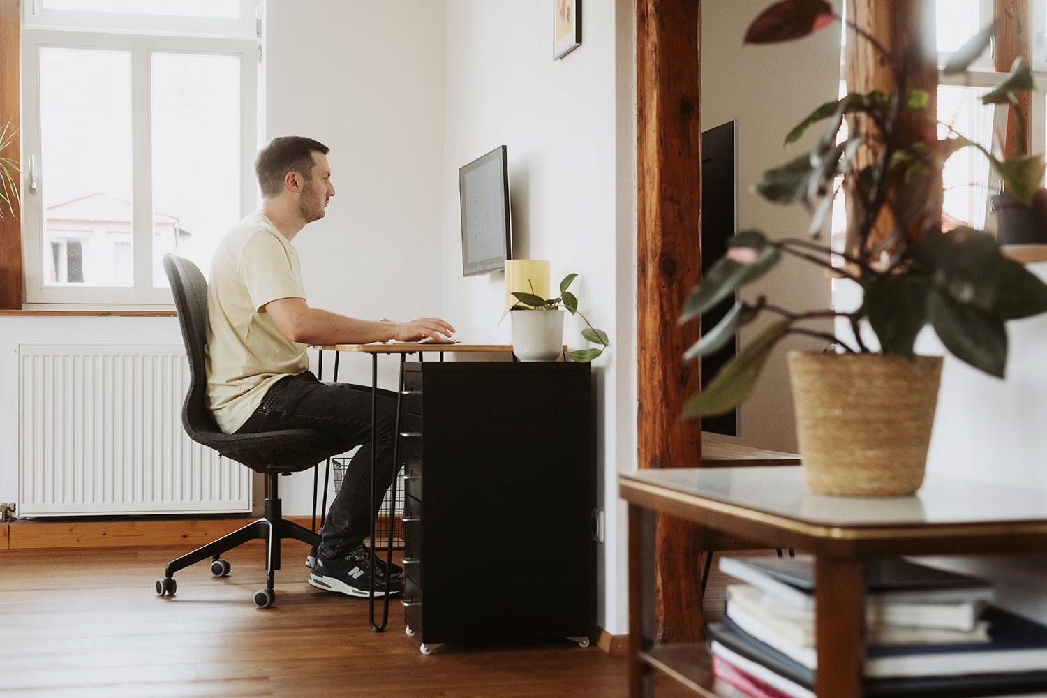 Peter Falkenberg am Schreibtisch in seinem Arbeitszimmer, durch eine Tür gesehen
