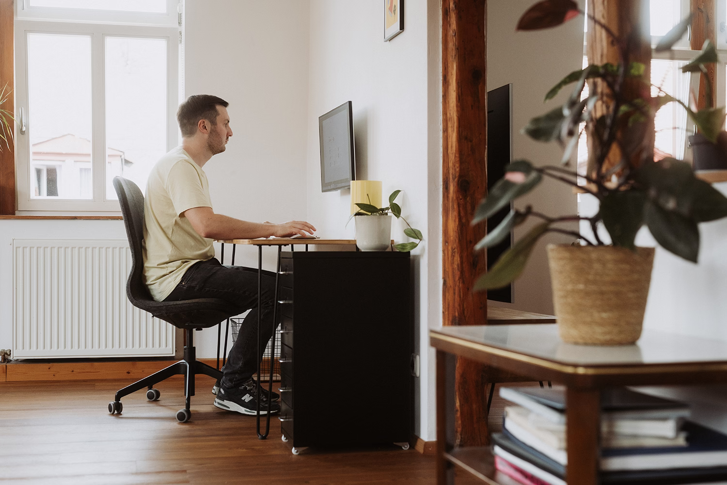 Peter Falkenberg am Schreibtisch in seinem Arbeitszimmer, durch eine Tür gesehen